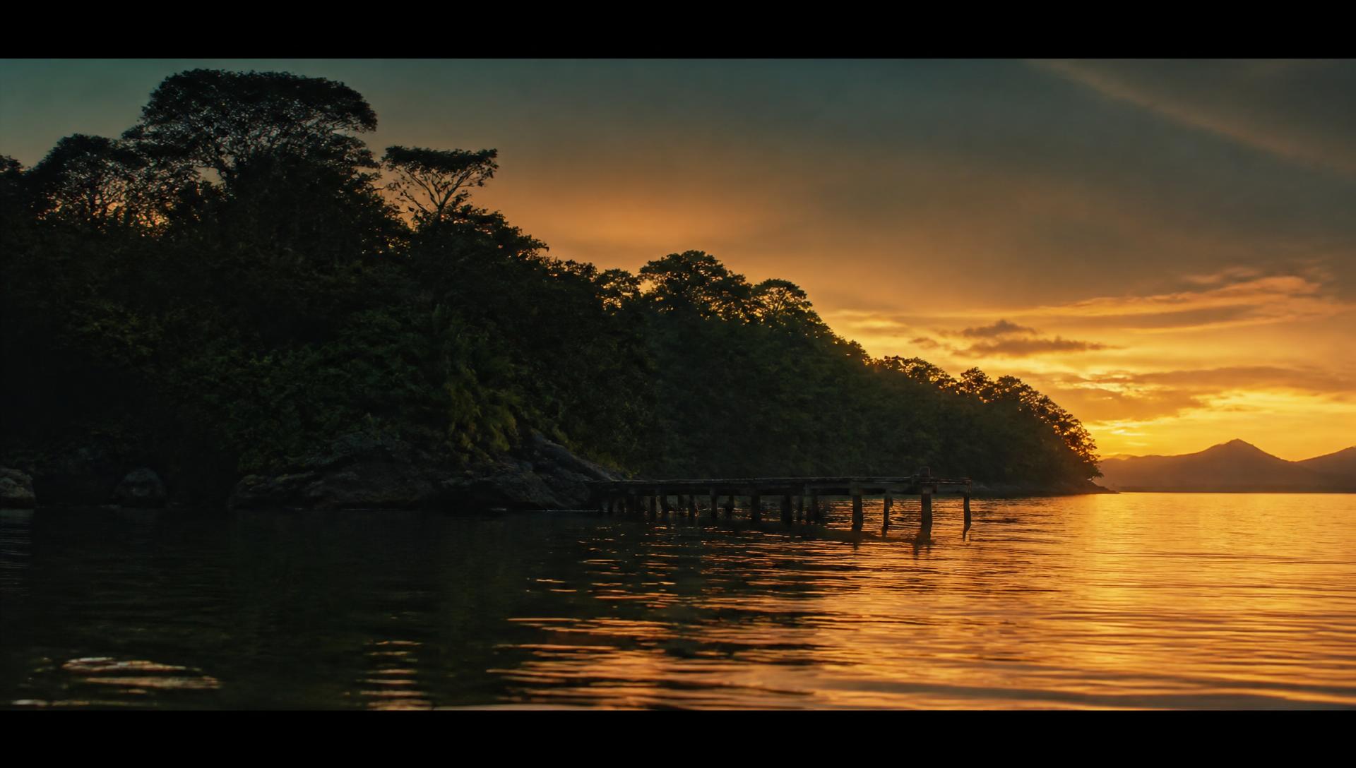 A ilha ao entardecer, com a silhueta da Mata Atlântica sobre o estuário dourado
